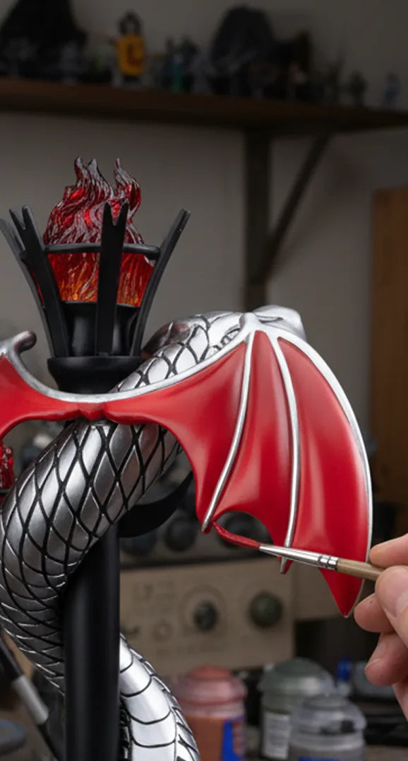 A painter finishing Sammy the Serpent's red wings by hand