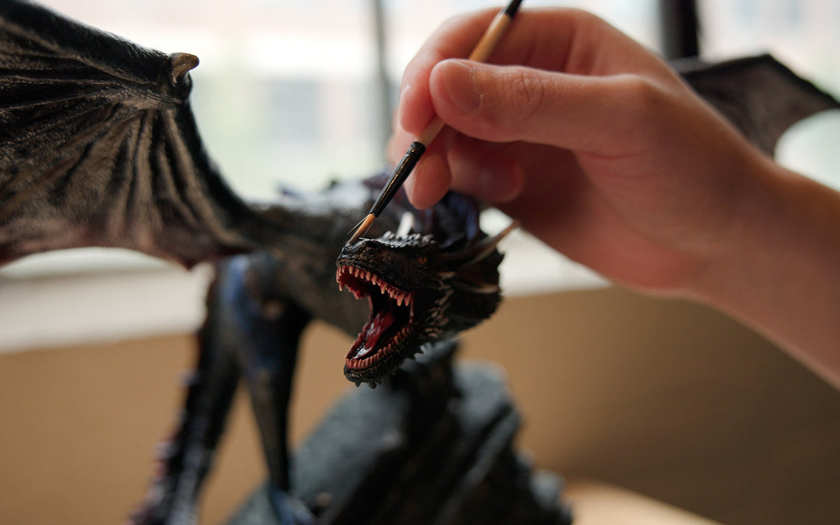 An artist painting Drogon by hand